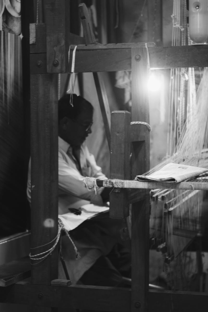 a man working on a loom in a dark room